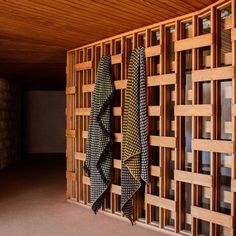 three ties hanging on the wall in front of wooden paneled room dividers and windows