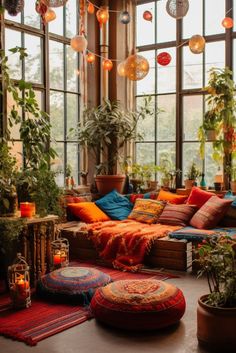 a living room filled with lots of plants and pillows on top of flooring next to large windows