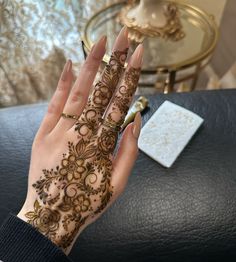 a woman's hand with henna on top of it and a table in the background