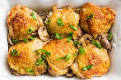 chicken thighs with mushrooms and parsley in a white casserole dish, ready to be eaten