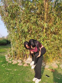 two people in front of a bamboo tree with one holding the other on his back