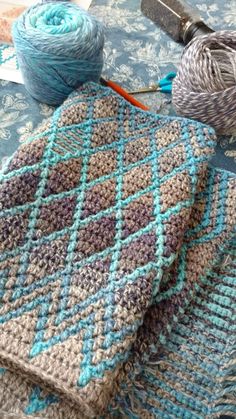 two knitted scarves sitting on top of a table next to yarn and scissors