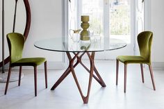 a glass table with four green chairs around it