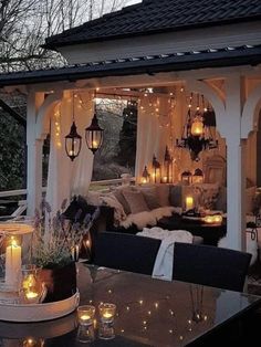 an outdoor living area with candles lit up on the ceiling and lights hanging from the roof