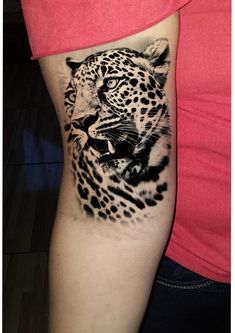 a woman's arm with a black and white tattoo of a leopard on it