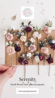 several small flower hair pins on top of a piece of brown paper with pink and white flowers