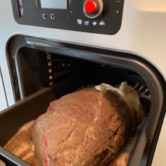 an open oven door with a roasting pan in it's center and food inside