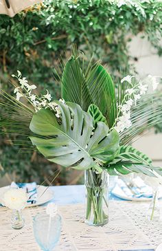 there is a vase with flowers and greenery on the table