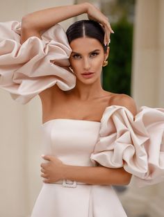 a woman in a white dress posing with her hands on her head