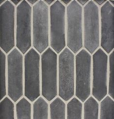 a gray and white tiled wall with hexagonal tiles on the bottom, in an irregular pattern