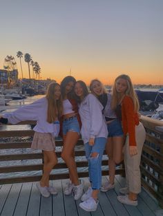 four girls posing on a pier at sunset