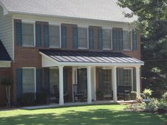 a large brick house with blue shutters on the front and side windows, covered by a white awning