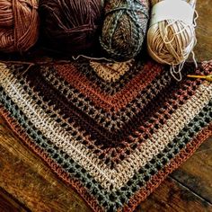 several balls of yarn sitting on top of a wooden floor next to some crochet