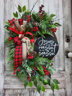 a christmas wreath hanging on the side of a wooden door with a chalkboard sign