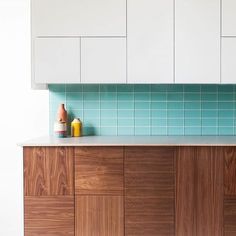 a kitchen with white cabinets and blue tile backsplashing on the counter top