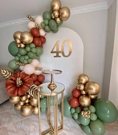 the balloon arch is decorated with gold, green and red balloons that spell out 40