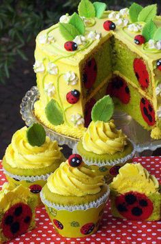 a yellow cake with ladybugs on it and cupcakes next to it