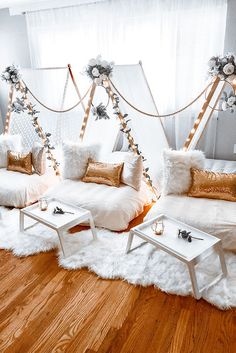 a living room filled with white furniture and gold pillows on top of a wooden floor