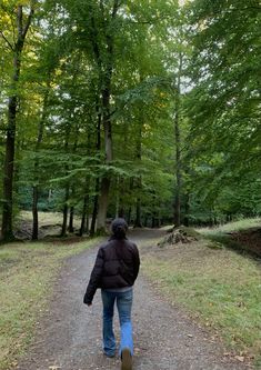 a person walking down a dirt road in the woods