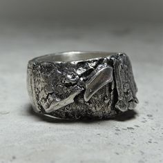 a silver ring sitting on top of a white table next to a gray wall and floor