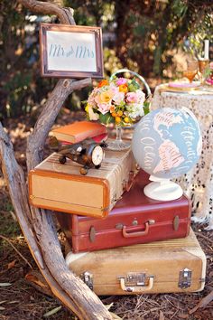 a table topped with an old suitcase and a vase filled with flowers next to a sign that says mr and mrs