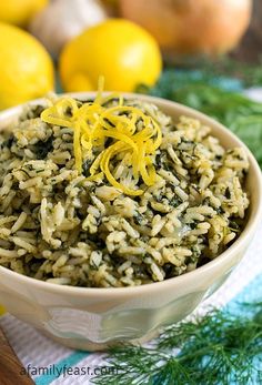 a bowl filled with rice and lemons on top of a table next to lemons