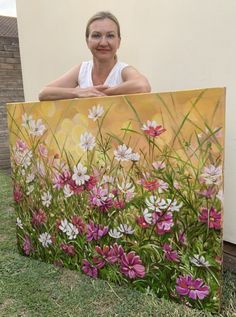 a woman standing behind a painting with flowers on it