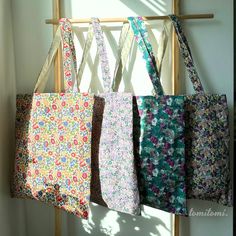 four bags hanging from a wooden rack in front of a window