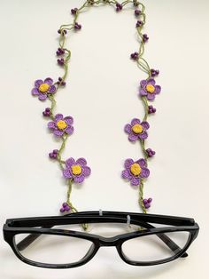 a pair of glasses sitting on top of a table next to a purple flower necklace