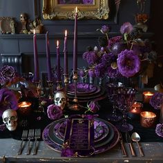 the table is set with purple flowers, skulls and candles for an elegant halloween dinner