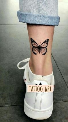 a woman's foot with a butterfly tattoo on the side of her leg,