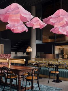 pink paper umbrellas hanging from the ceiling in a restaurant