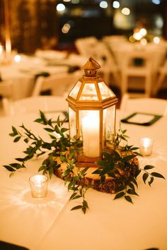 a lantern on top of a table with greenery