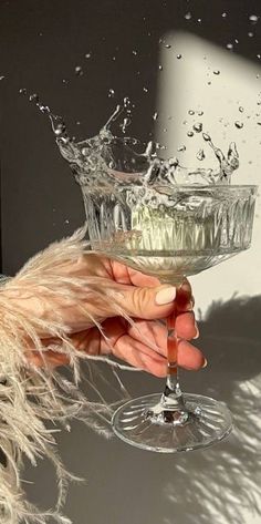 a person holding a wine glass with water splashing out of the top and bottom