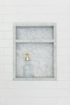 a bathroom with marble shelves and gold faucet in the corner on the wall