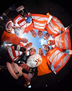 a group of people standing in a circle holding orange and white striped umbrellas on top of each other