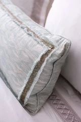 a close up of a pillow on a bed with white linens and pillows in the background