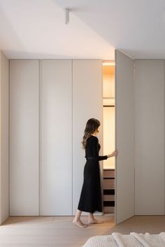 a woman in a black dress is opening the closet door to look into her bedroom