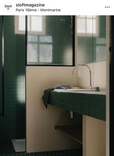 a green tiled bathroom with a sink and mirror