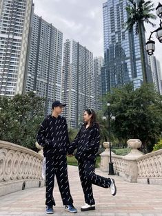 two people standing on a bridge in front of tall buildings