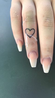 a woman's hand with a heart tattoo on her left thumb and ring finger