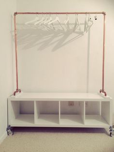 a white shelf sitting in the corner of a room next to a wall with a plant on it