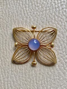 1951 Modernist Four Petal Flower Brooch with Chalcedony Stone in 18k gold - Stockholm, Sweden by Stigbert A wonderful well-sized and graphic 4-petal flower brooch by the Modernist master, Stig Engelbert. Each petal is formed as if the lines from his sketch book just popped into form around a perfect mystical periwinkle chalcedony cabochon. It looks a bit like a crystal ball, yes? This brooch was made in 1951 by maker Stigbert for Engelbert Heribert in Stockholm, Sweden. Piece measures about 1.5 Art Deco Yellow Gold Collectible Brooches, Mid-century Cabochon Brooch For Gift, Mid-century Cabochon Brooches For Gifts, Mid-century Cabochon Brooch Gift, Mid-century Yellow Gold Brooch For Gifts, Art Nouveau Gold Brooch With Cabochon, Art Deco Yellow Gold Hallmarked Brooches, Mid-century Yellow Gold Brooch Jewelry, Mid-century Yellow Gold Brooch