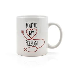 a white coffee mug with the words you're my person on it and a stethoscope