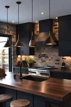 a kitchen with black cabinets and wooden counter tops, hanging lights over the stove top