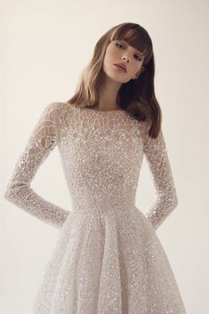 a woman in a short white dress with long sleeves and sequins on it