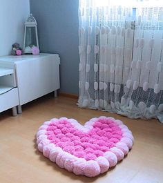 a pink heart shaped rug sitting on the floor in front of a window with curtains