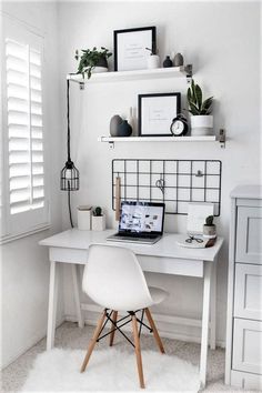 a white desk with a laptop computer on top of it next to a shelf filled with potted plants