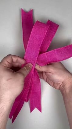 two hands are tying a pink ribbon together