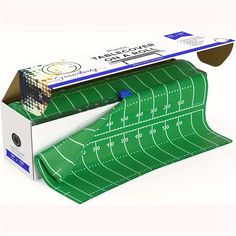 a green football field wrapping tape in a cardboard box with the lid open to show it's inside